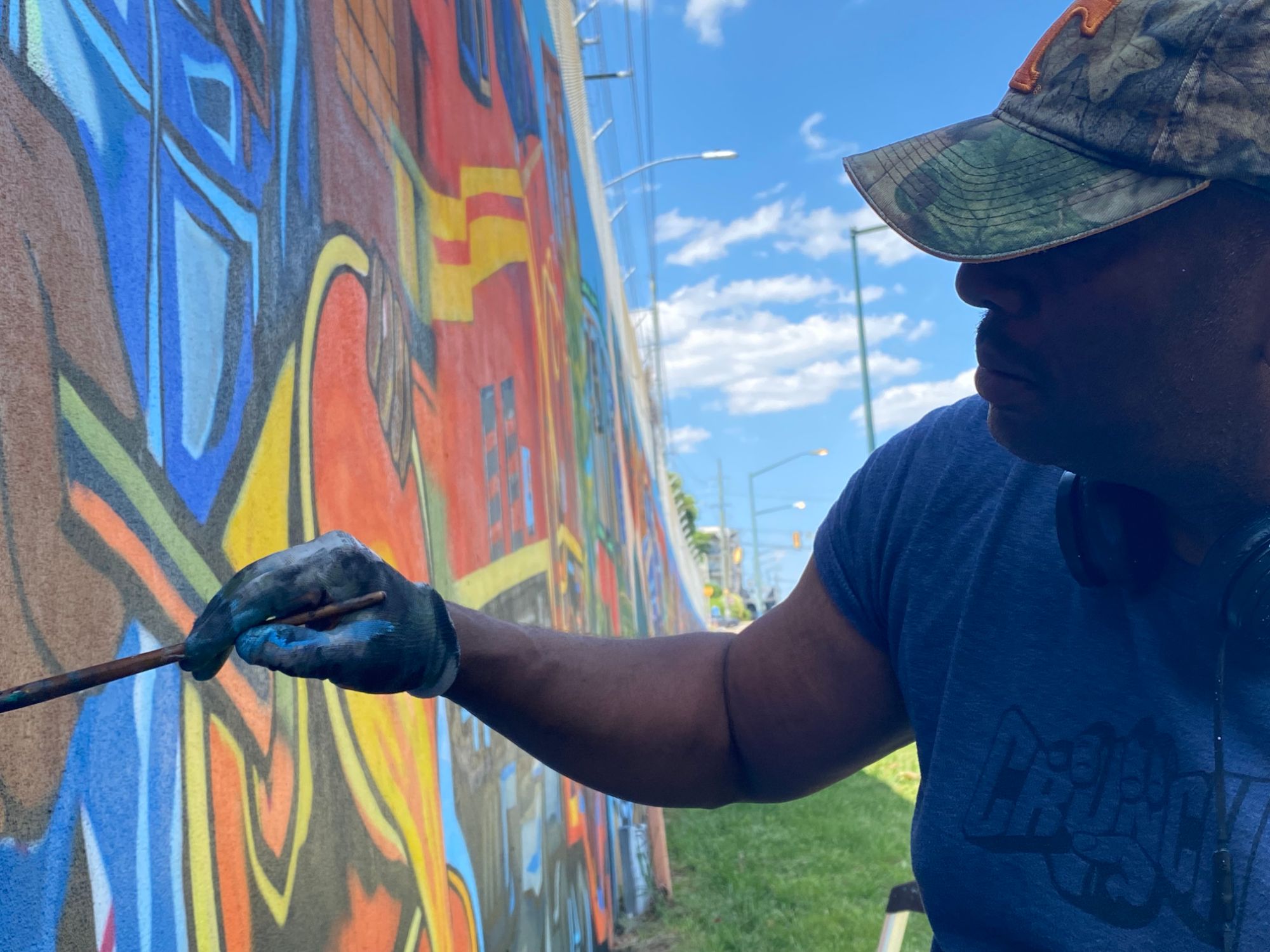 Close-up of Corey Barksdale's hand painting color detail on the Blandtown mural, Atlanta