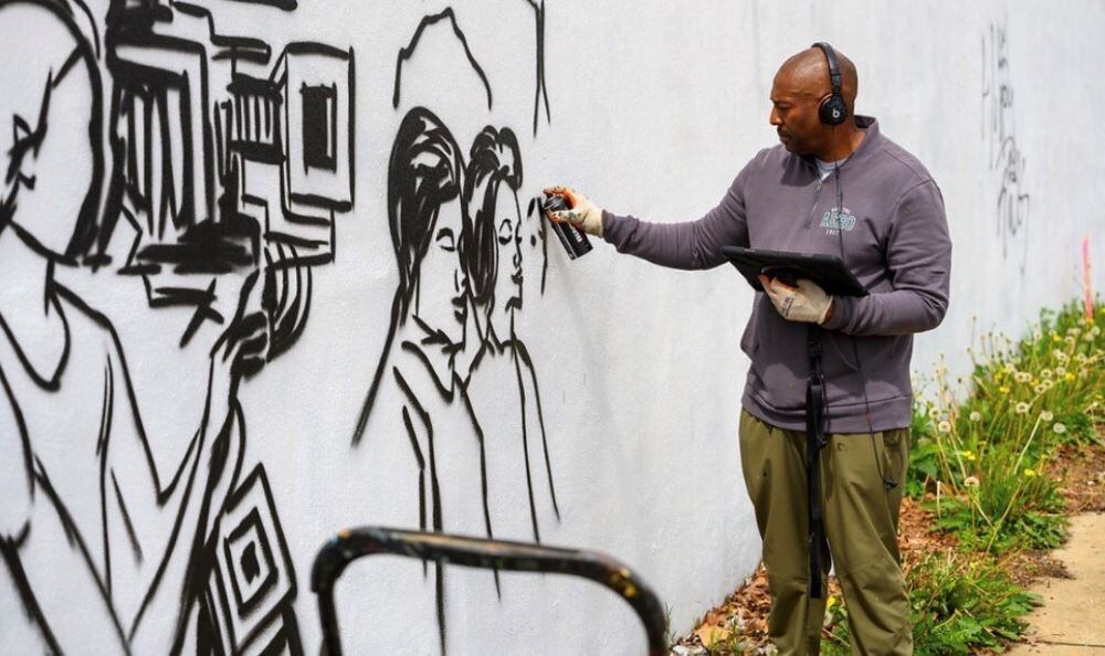 Corey Barksdale freehand spray-painting a mural outline live at an outdoor Atlanta event