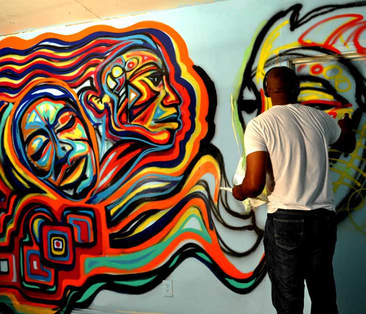 Corey Barksdale live painting a vibrant African American contemporary art mural indoors